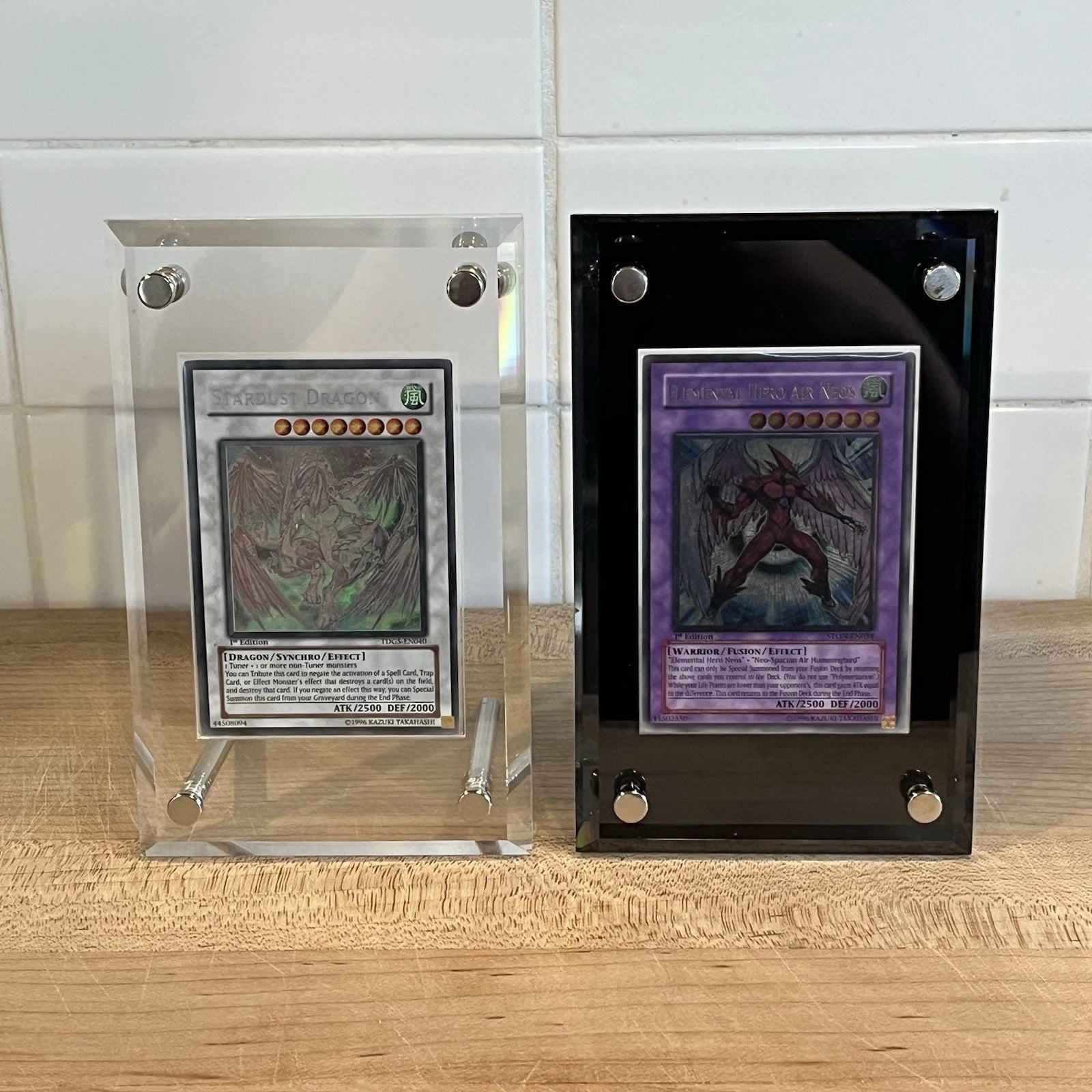 Two Yugioh cards on display in acrylic screwdown cases that come in the colors black and clear.