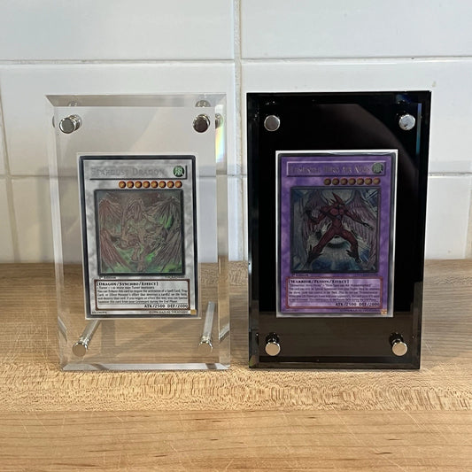 Two Yugioh cards on display in acrylic screwdown cases that come in the colors black and clear.