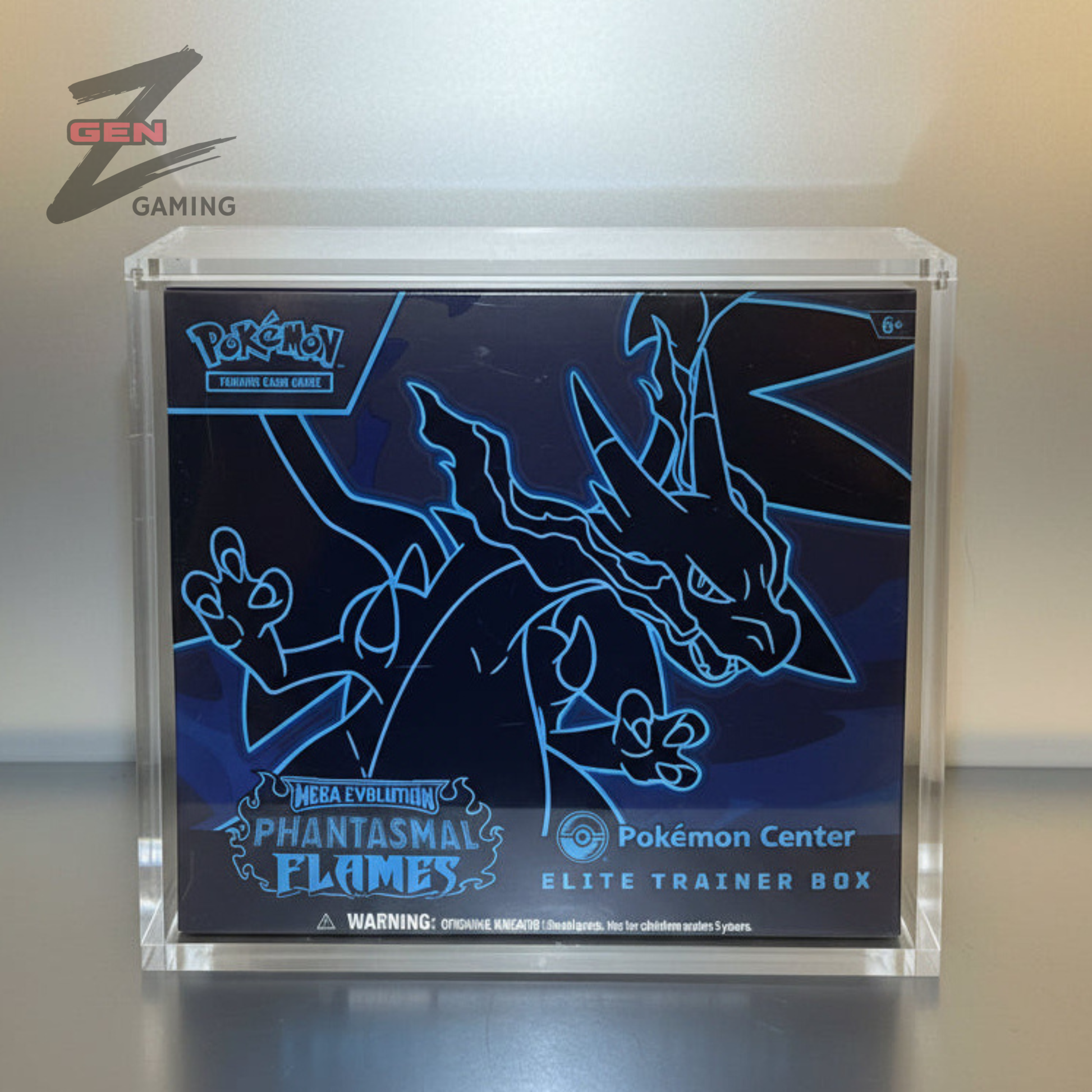Pokémon Center Elite Trainer Box for Phantasmal Flames, displayed inside a clear acrylic case on a silver surface.