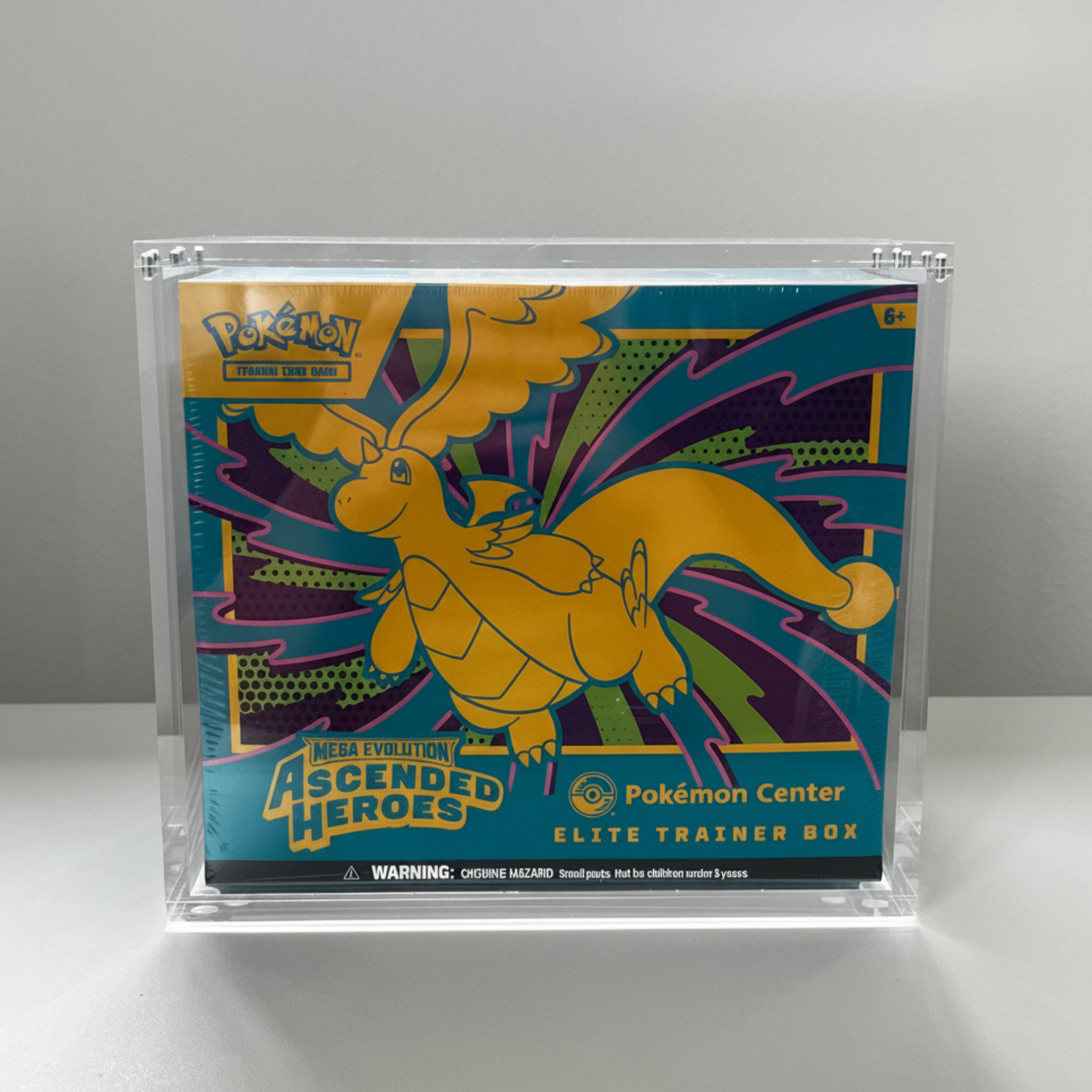 A Pokémon Center Ascended Heroes Elite Trainer Box (ETB) on display inside a clear Acrylic Protective Case by GenZGaming. The box features a colorful graphic of the Yellow Dragon with a teal and purple background, and is displayed on a light gray surface with a gray background.