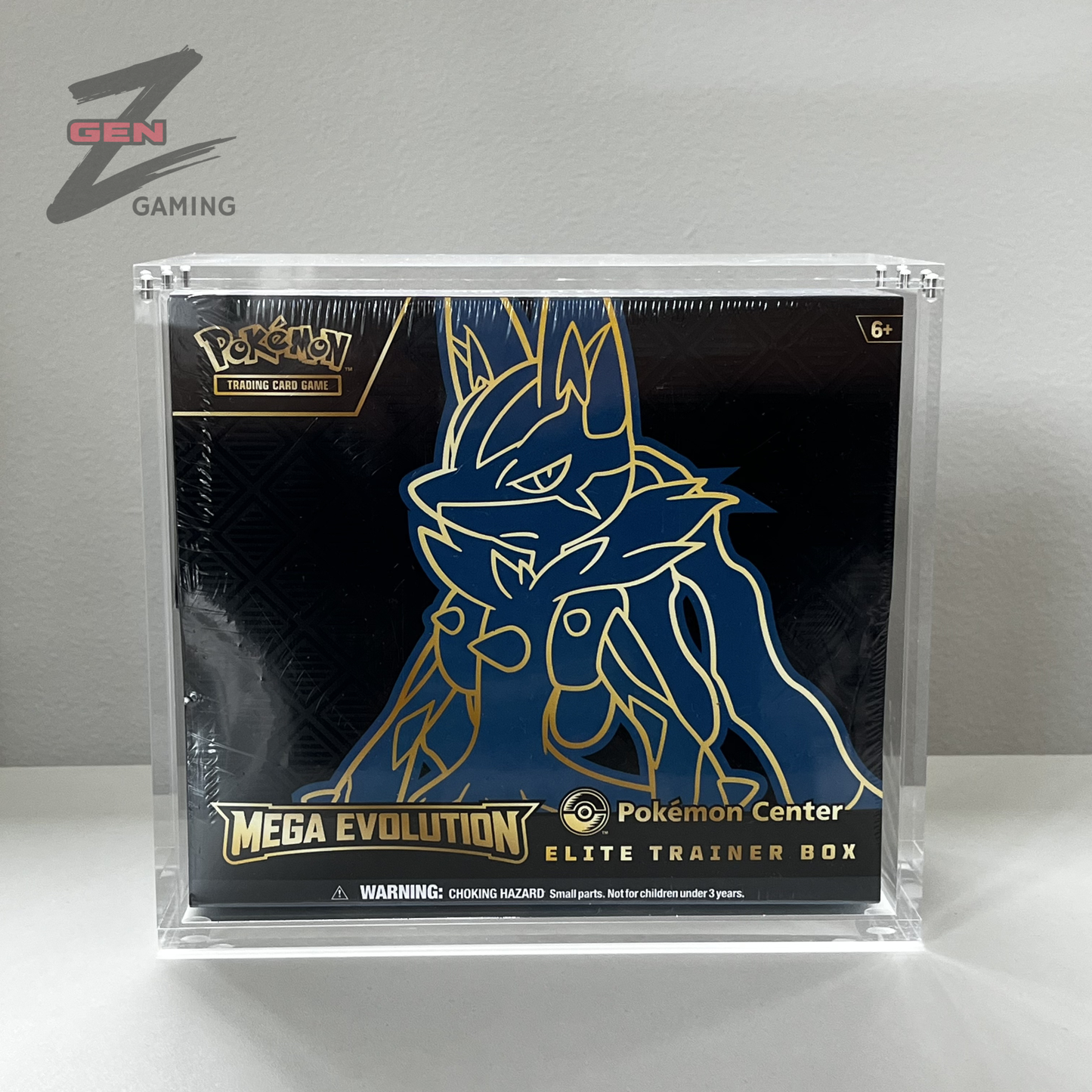 A sealed Pokémon Center Mega Evolution Elite Trainer Box ETB in a clear acrylic protective case, photographed against a plain light gray wall and surface.