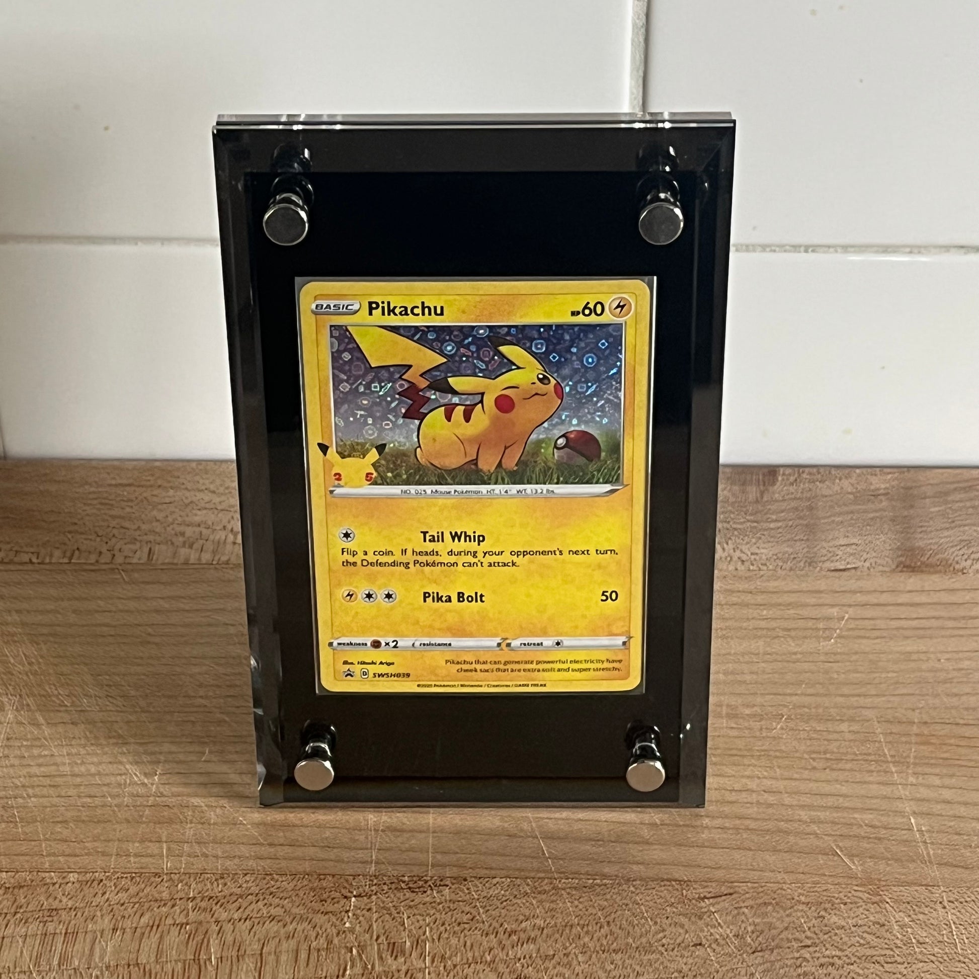 Pikachu trading card in a Black protective case on a wooden surface.