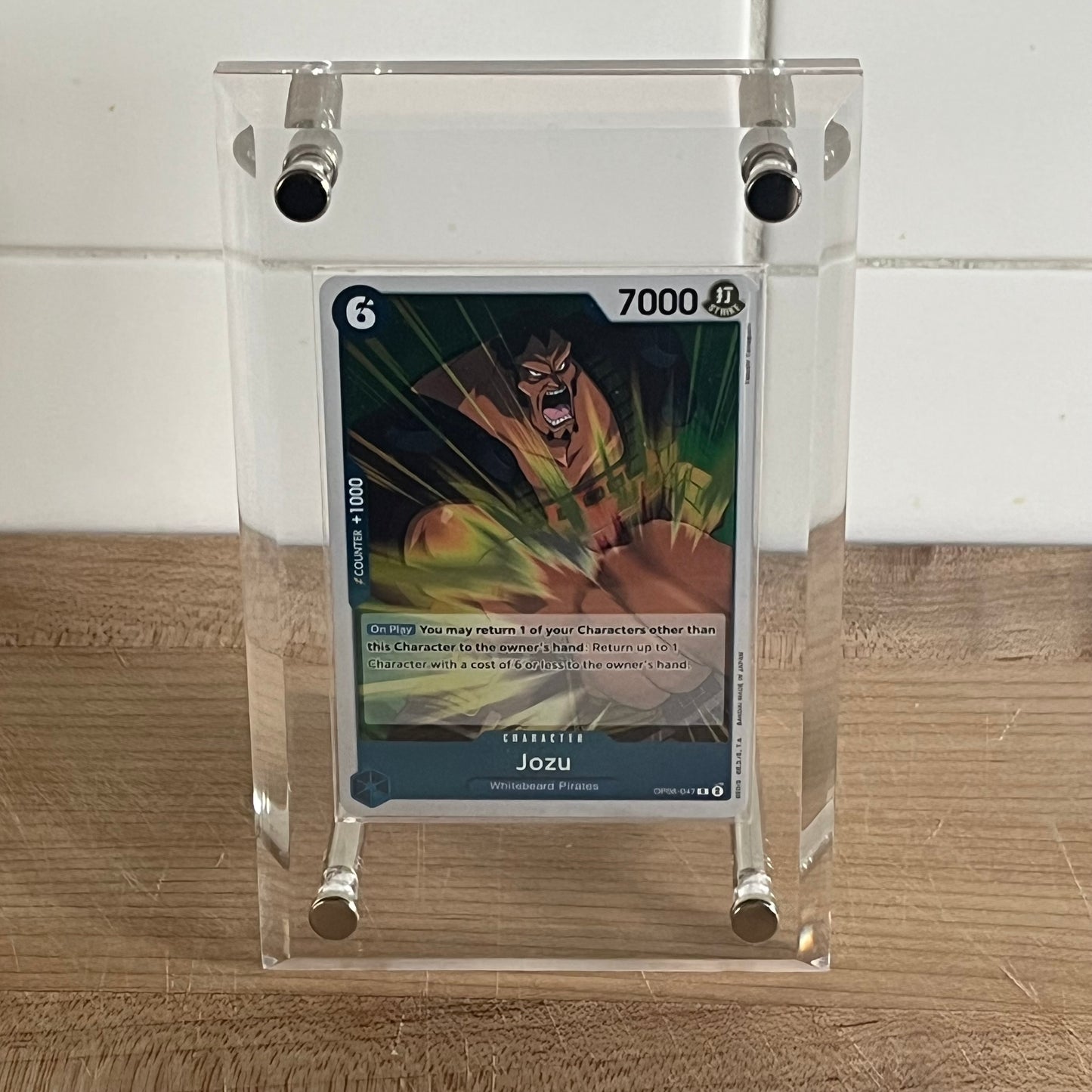 A One Piece TCG card displayed in a clear protective acrylic screwdown case.